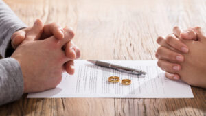 Hands of husband and wife on table with divorce papers.